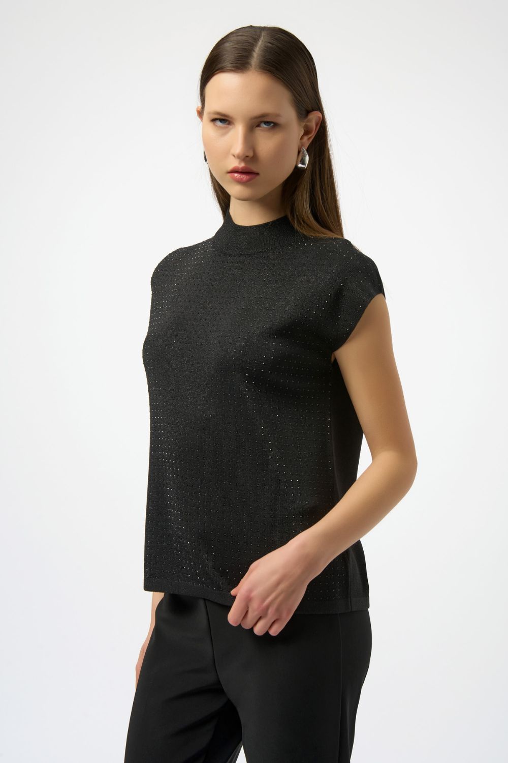 Woman wearing a black sleeveless top and black pants on a white background