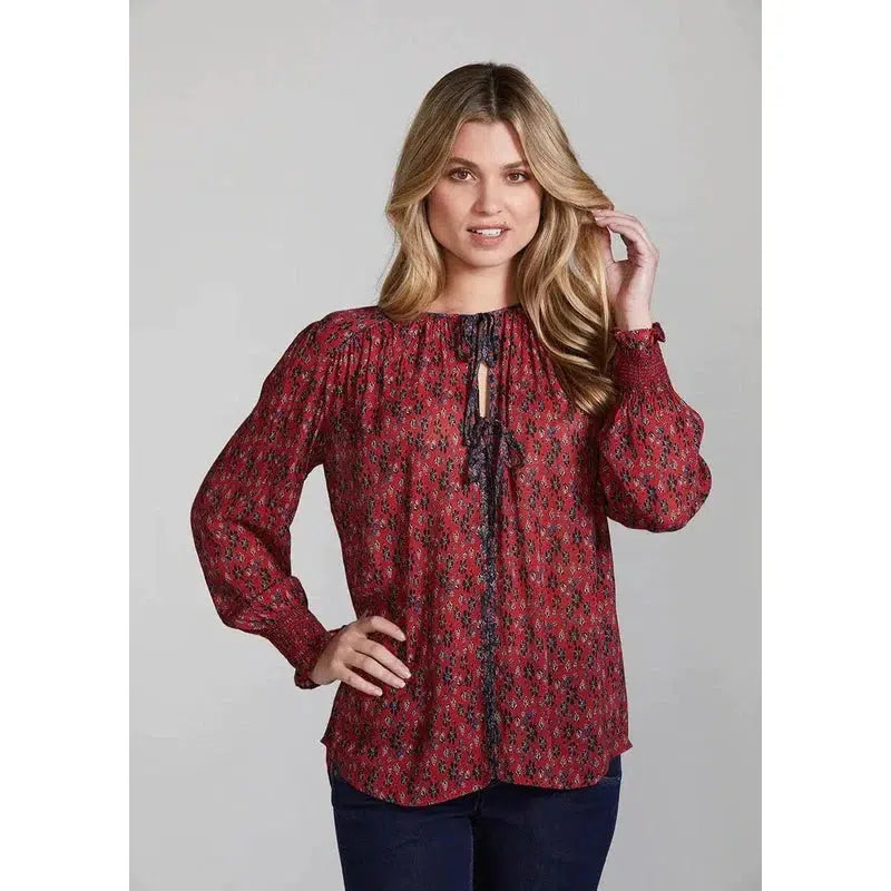 Front view Red. Soft and fluid silhouette. Gathers around the shoulders and sleeves. Delicate and feminine floral print. Contrast binding and tie details at the centre front. A shirred cuff with contrast embroidery thread detail. Sizes 10 -16. 63% Viscose 37 % Rayon. Hand wash.